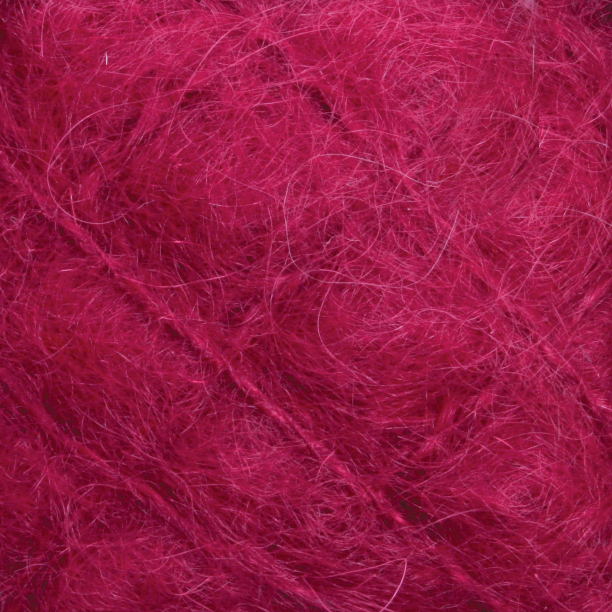 Close-up image of fuzzy, deep pink yarn with visible fibers and strands. The texture appears soft and slightly tangled, highlighting the fine details of the luxurious Victorian Brushed Mohair Yarn from Caledonian Dye Works.