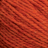 Close-up of an orange-colored Harrisville Shetland Yarn - Unwashed Cones by Harrisville Designs. The image showcases the texture of the yarn fibers tightly twisted together, clearly highlighting the strands and slight fuzziness typical of wool or a wool-blend material, often used in Fair Isle knitting designs.