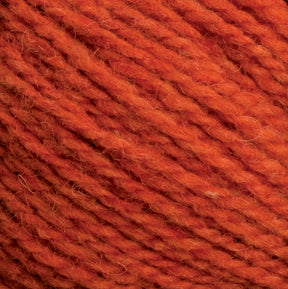 Close-up of an orange-colored Harrisville Shetland Yarn - Unwashed Cones by Harrisville Designs. The image showcases the texture of the yarn fibers tightly twisted together, clearly highlighting the strands and slight fuzziness typical of wool or a wool-blend material, often used in Fair Isle knitting designs.