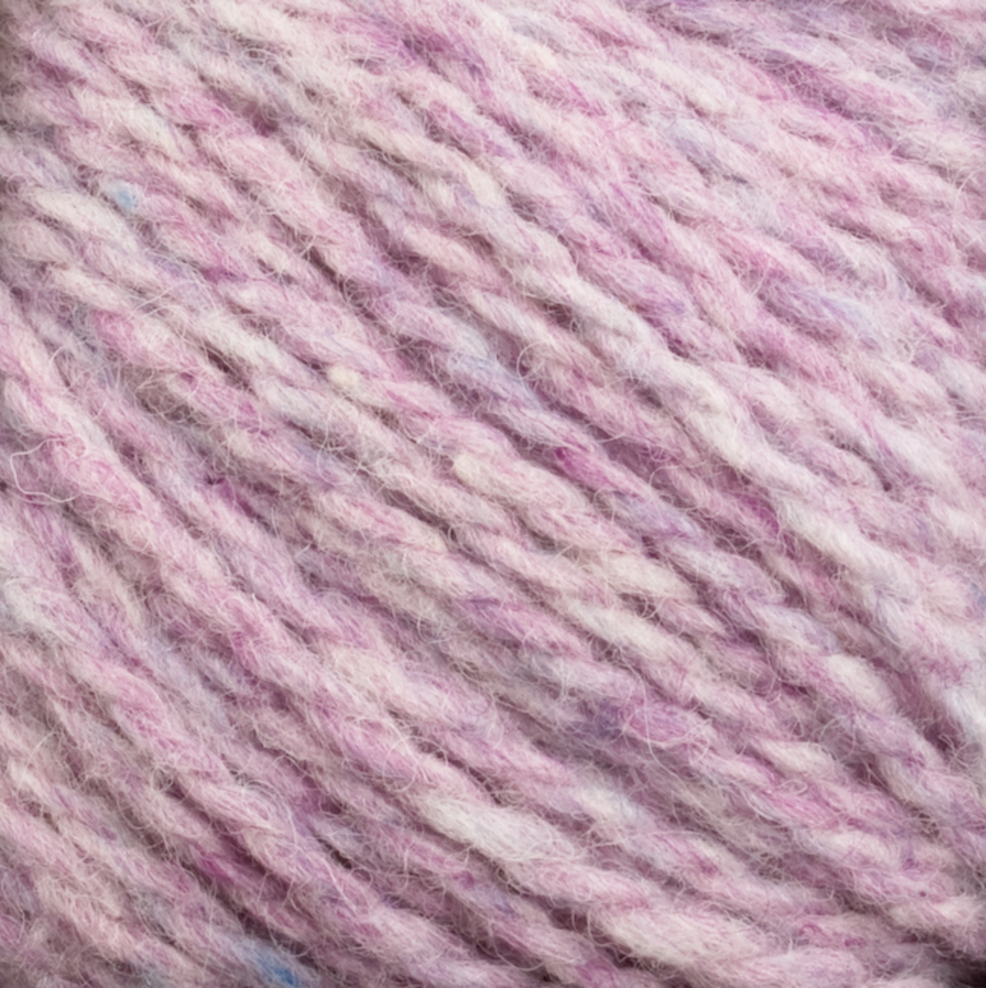 Close-up image of soft, twisted Harrisville Shetland Yarn - Unwashed Cones by Harrisville Designs in shades of pink, purple, and white. The texture appears fluffy and slightly fuzzy, suggesting it is made from this warm yarn, ideal for knitting or crocheting lightweight blankets.