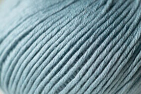 Close-up image of Jo Sharp Soho Summer DK Cotton yarn in light gray. The texture of the lightweight cotton from Kingfisher Yarn & Fibre is soft and slightly shiny, with the individual strands tightly twisted together. The overall look is smooth, showcasing the fine quality perfect for summer yarn projects.