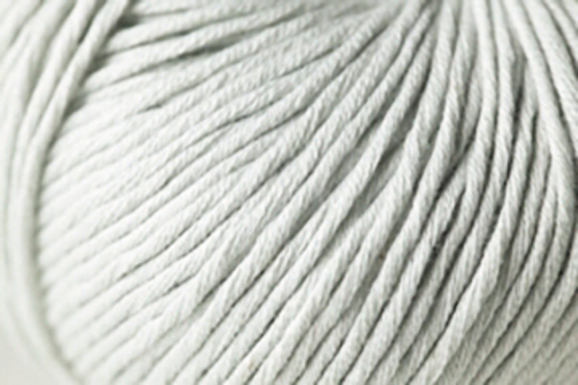 Close-up photo of a ball of Jo Sharp Soho Summer DK Cotton by Kingfisher Yarn & Fibre, with tightly wound strands clearly visible, showcasing its texture and softness.