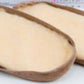 Two oval-shaped, flat, brown items from Bryson Distributing, Inc. are shown side by side on a light-colored surface. They have a textured appearance and are light brown on the inside with slightly darker edges. These products are the Suede leather and fleece soles designed for comfort and durability.