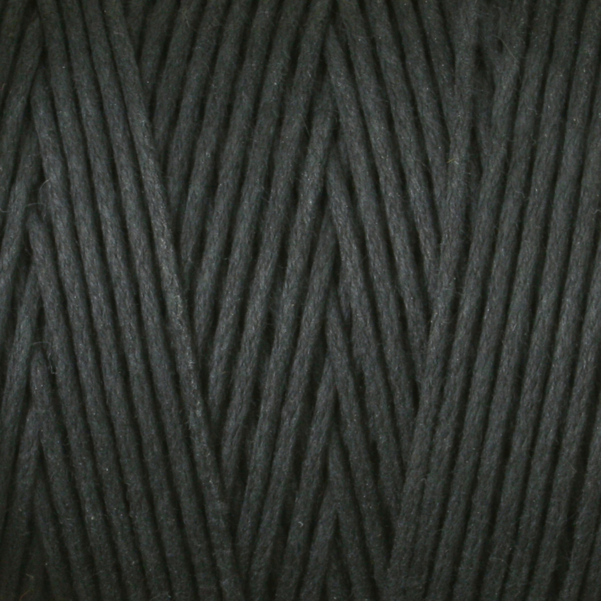 A close-up view of Stuart C. Hurlbert & Co.'s #9 Cotton Lacing Cord intricately wound into a ball. The dark gray cord is smooth and tightly arranged, creating a neat, diagonal pattern reminiscent of the precision seen in crafting braided rugs.