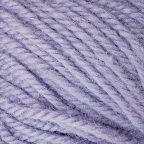 Close-up image of a light purple Halcyon Deco Rug Wool from Caledonian Dye Works. The texture of the 100% wool fibers is clearly visible, showcasing its soft and fluffy appearance, while the strands are tightly wound together, highlighting the detailed, twisted pattern of this versatile yarn.