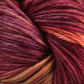 Close-up of a ball of Malabrigo Arroyo yarn from Malabrigo Yarn, featuring rich, variegated colors including shades of purple, red, and orange. The sport weight superwash merino wool yarn is tightly wound, showcasing its soft and textured fibers.