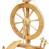 The Kromski Sonata Double-Treadle Spinning Wheel by Kromski North America is a traditional wooden spinning wheel that boasts a large wheel with multiple spokes. It features double treadles at the bottom and includes a bobbin and flyer assembly at the top. This portable Sonata spinning wheel is expertly designed for spinning fibers into yarn or thread.