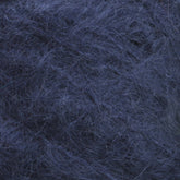 Close-up image of dark blue, fuzzy yarn. The texture appears soft and wooly, with fibers loosely intertwined and some stray strands, reminiscent of the luxurious Victorian Brushed Mohair Yarn in a large skein from Caledonian Dye Works.