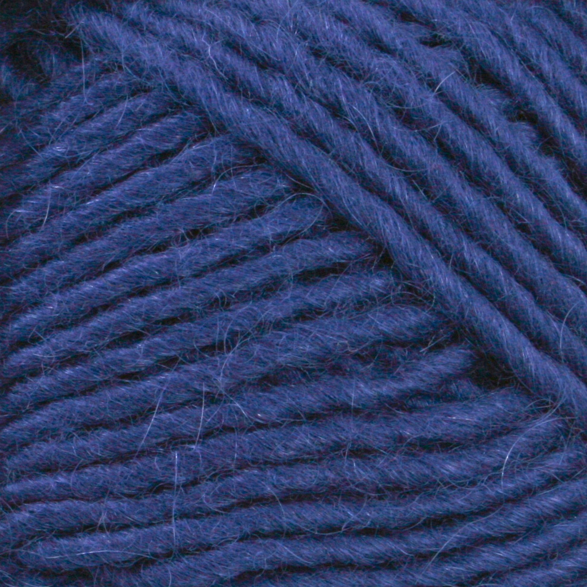 Close-up image of Lamb's Pride Bulky Yarn in dark blue, showing the texture and intertwined fibers. The yarn, from Brown Sheep, is thick and soft with a slightly fuzzy appearance, making it ideal for knitters and crocheters crafting cozy garments or accessories like Icelandic sweaters.