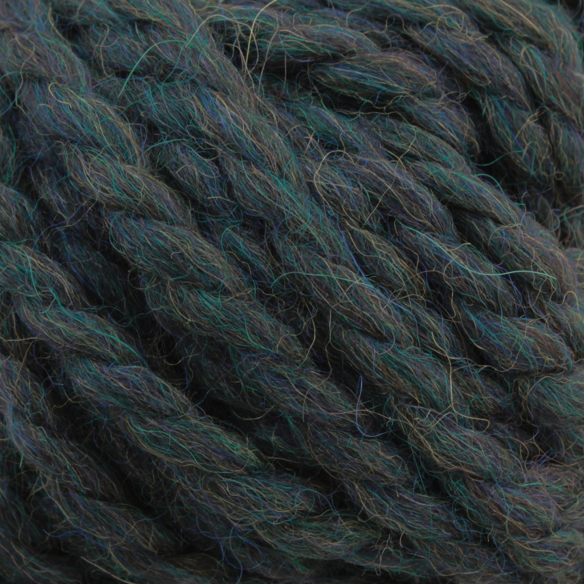 Close-up view of Plymouth Yarn Co.'s Baby Alpaca Grande, a thick, multi-colored yarn showcasing intertwined fibers in shades of dark green, blue, and hints of brown. The ultra-soft texture appears slightly fuzzy, suggesting a likely wool blend and bulky weight.