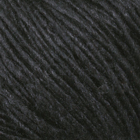 Close-up image of Malabrigo Silky Merino luxury yarn in dark gray or black, showcasing its slightly shiny texture. The fibers appear soft and tightly spun, creating a smooth and consistent surface indicative of the high quality associated with Malabrigo Yarn.