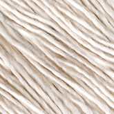 The close-up image showcases strands of Henry's Attic Soft Twist Natural Silk Yarn. This yarn consists of twisted natural fibers, appearing soft and slightly uneven in thickness, creating a textured background. The colors range from off-white to pale beige, giving it a natural and organic look perfect for hand washing.