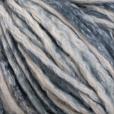 Close-up of Cumulus Cotton by Juniper Moon Farm in shades of blue, gray, and white. The thick strands are twisted together, highlighting the texture and variations in color. The image emphasizes the fibrous and soft nature of the durable chainette construction by Knitting Fever / Euro Yarns.