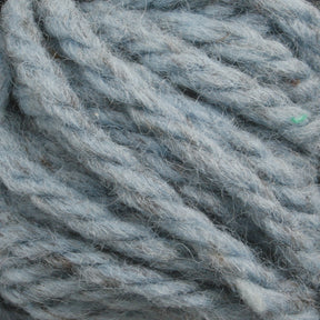 Close-up of thick, twisted light blue Halcyon Yarn Classic Rug Wool | Strand by Caledonian Dye Works, with visible fibers and texture. The yarn appears soft and slightly fuzzy, suggesting it may be made from hand-dyed natural materials. The image features intricate detail of the wool strands, ideal for rug weavers seeking quality.