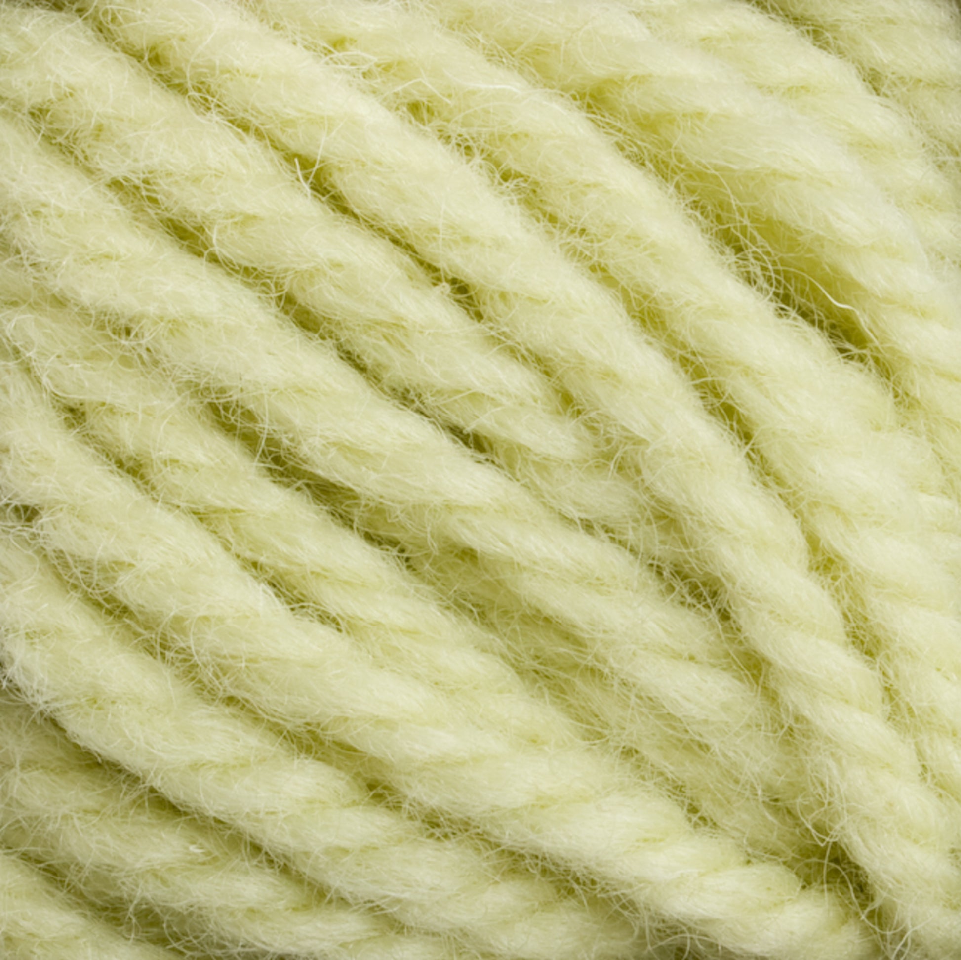 Close-up image of several strands of thick, soft, light yellow yarn, twisted together. The texture appears fluffy and slightly fuzzy, suggesting it is made from Halcyon Yarn Classic Rug Wool by Caledonian Dye Works, ideal for knitting or crocheting warm, cozy items.