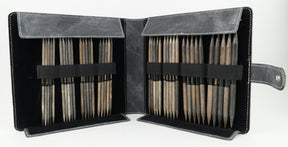 A black case is opened to reveal an array of Lykke Double-Point Knitting Needles from Knitting Fever / Euro Yarns, neatly organized in elastic loops. The 6" needles, available in various sizes and crafted from wood, are secured in the case which features white stitching and a snap closure. This exquisite needle set comes with a lifetime guarantee.