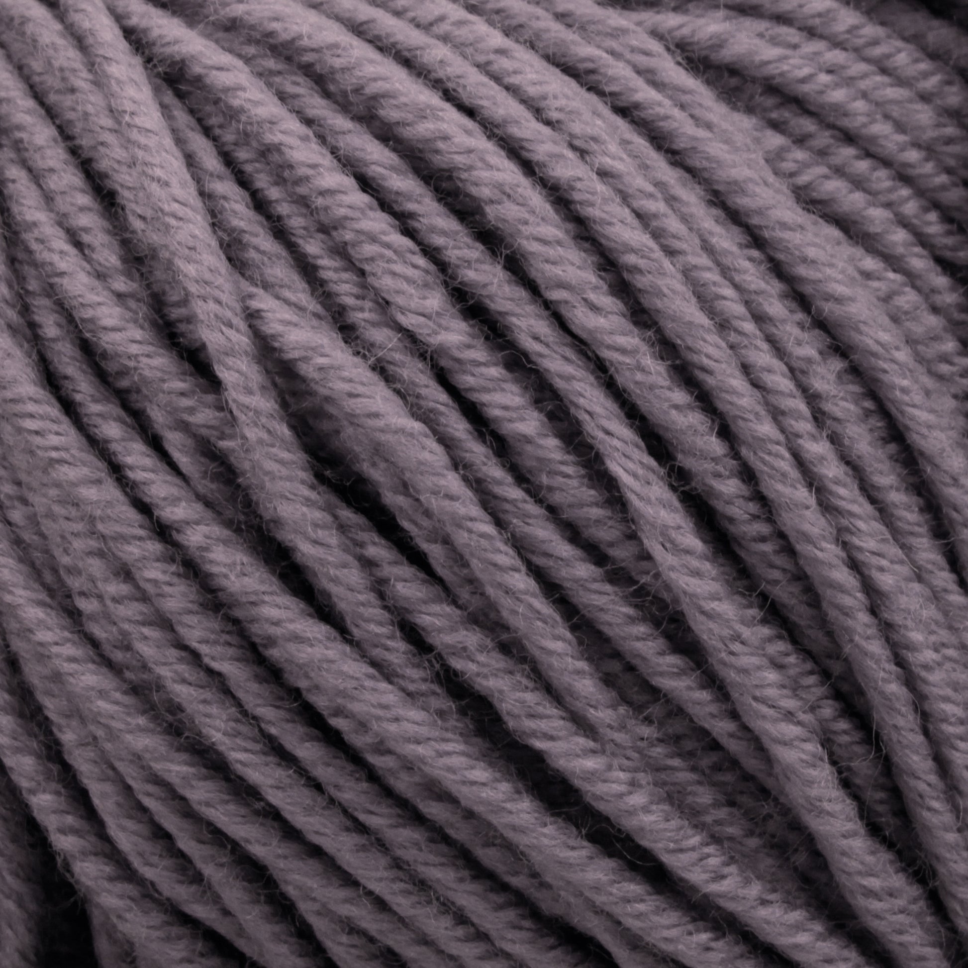 Close-up image of a bundle of Plymouth Select Worsted Merino Superwash by Plymouth Yarn Co. The thick, dark gray strands are tightly wound together, creating a textured and detailed pattern that enhances stitch definition.