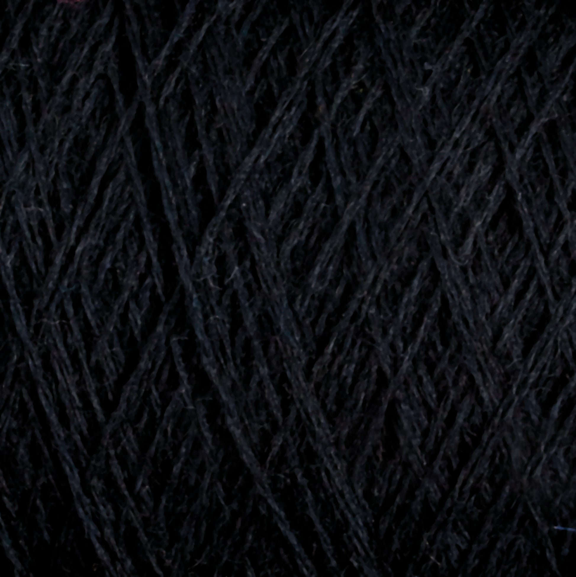 Close-up image of JaggerSpun Maine Line 2/20 Yarn by Jagger Brothers, Inc. in black, wound into a ball, showcasing detailed texture and fibers. The worsted spun yarns appear tightly wound and exhibit a smooth, consistent appearance.