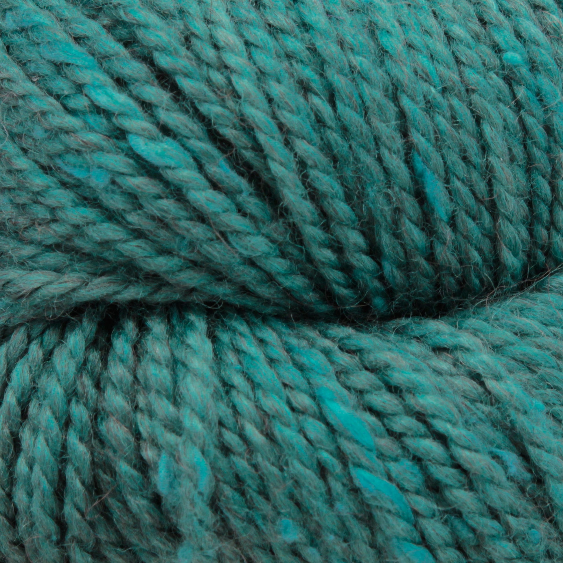 Close-up of thick, twisted teal Acadia by The Fibre Co. (UK) Ltd yarn. The texture is highly detailed, showcasing its fibrous material and subtle tweed effect with rich color variations.