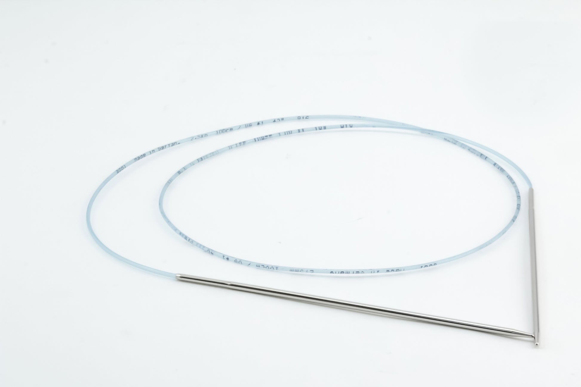 A slender, flexible medical or scientific tube with a long, translucent body and metallic ends is coiled on a white background. Reminiscent of Skacel’s Addi Turbo Circular Knitting Needles used in specialized procedures or equipment, the tube's precision mirrors that seen with these high-quality tools.