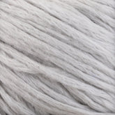 Close-up of soft, thick strands of Cumulus Cotton by Juniper Moon Farm in light gray, almost white. The texture appears fluffy and slightly uneven, showcasing the fibers and slight variations in shade. With its durable chainette construction, the yarn is coiled and intertwined in a way that suggests it is ready for knitting or crafting. This product is crafted by the respected brand Knitting Fever / Euro Yarns.