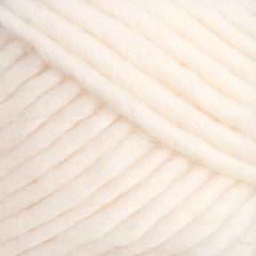 Close-up of thick, soft, and slightly fuzzy cream-colored Lamb's Pride Bulky Yarn by Brown Sheep. The strands are neatly arranged and appear to be made of a wool-like material. The texture looks warm and perfect for cozy knitting or crocheting projects like woven blankets or Icelandic sweaters.