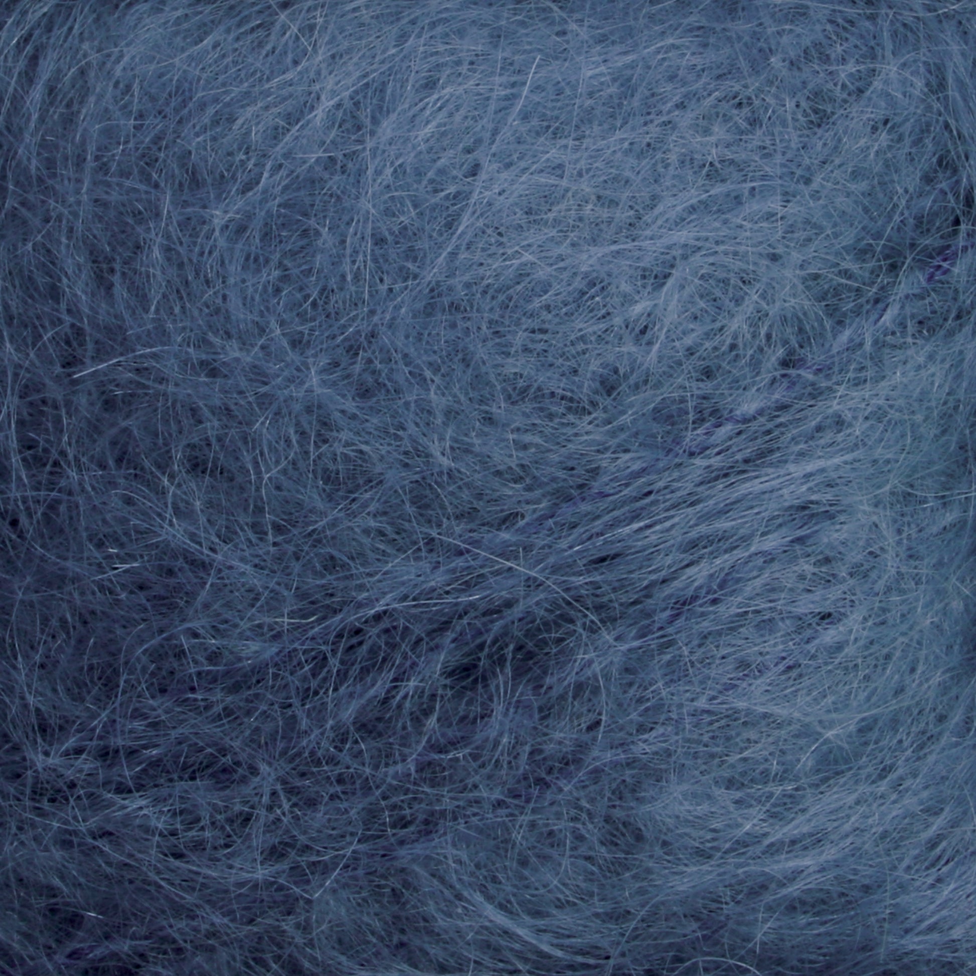 Close-up image of the Victorian Brushed Mohair Yarn | Mini Skein by Caledonian Dye Works, showcasing the soft, fuzzy blue fibers with varying shades that create a textured, fibrous surface. The thin and interwoven fibers give this luxurious mohair a fluffy and delicate appearance reminiscent of classic Victorian yarns.