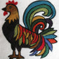 A vibrant, stylized rooster is depicted in felt art, crafted from The Felting Studio's Needle Felting Tapestry Kit. The rooster features a black body with multicolored feathers, including shades of green, red, yellow, and blue. Its tail feathers are especially elaborate and colorful, standing out against the white background.