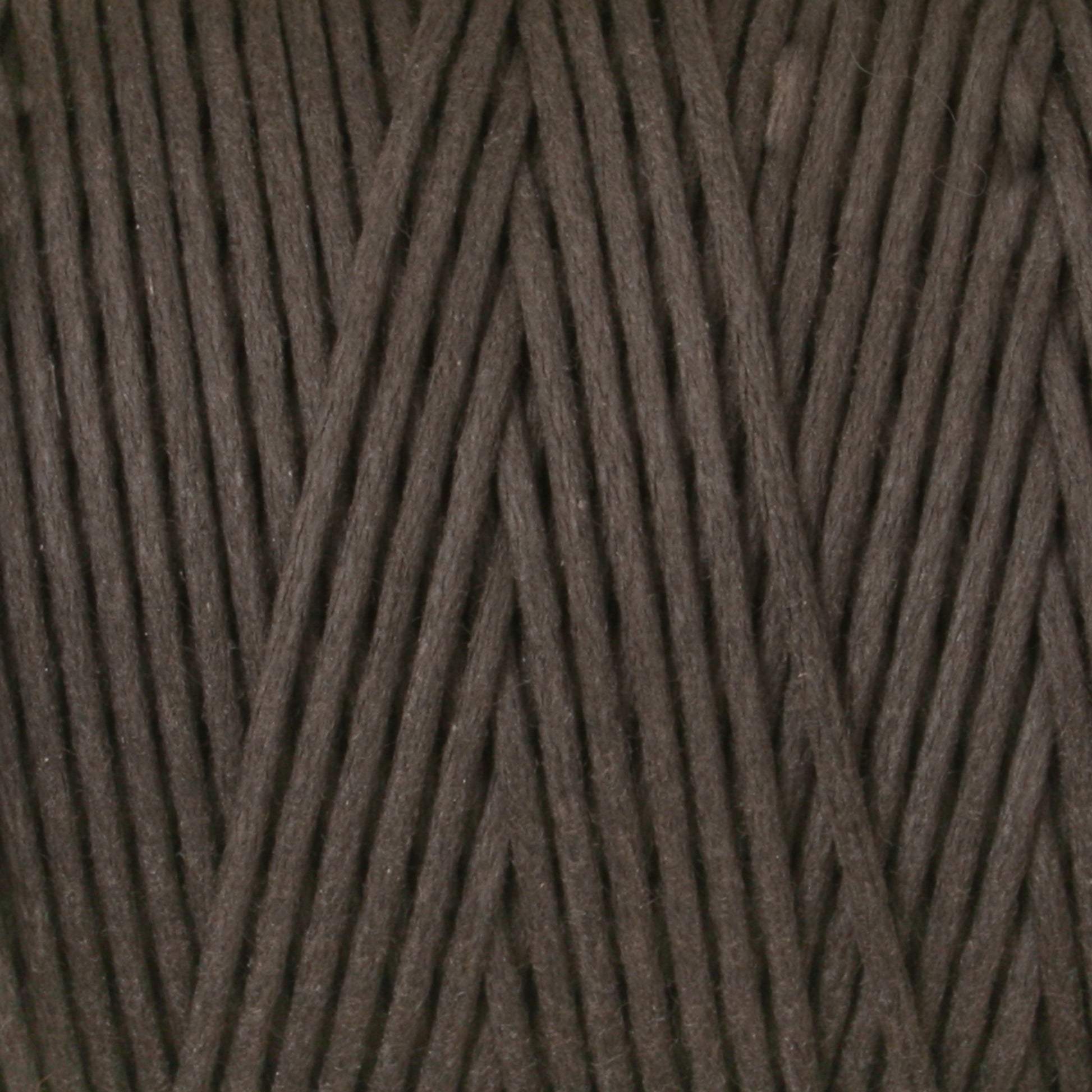 A close-up image of the #9 Cotton Lacing Cord from Stuart C. Hurlbert & Co. The dark brown fibers are neatly wound together in a crisscross pattern, reminiscent of the meticulous work of rug braiders, showcasing the texture and thickness of the cord.