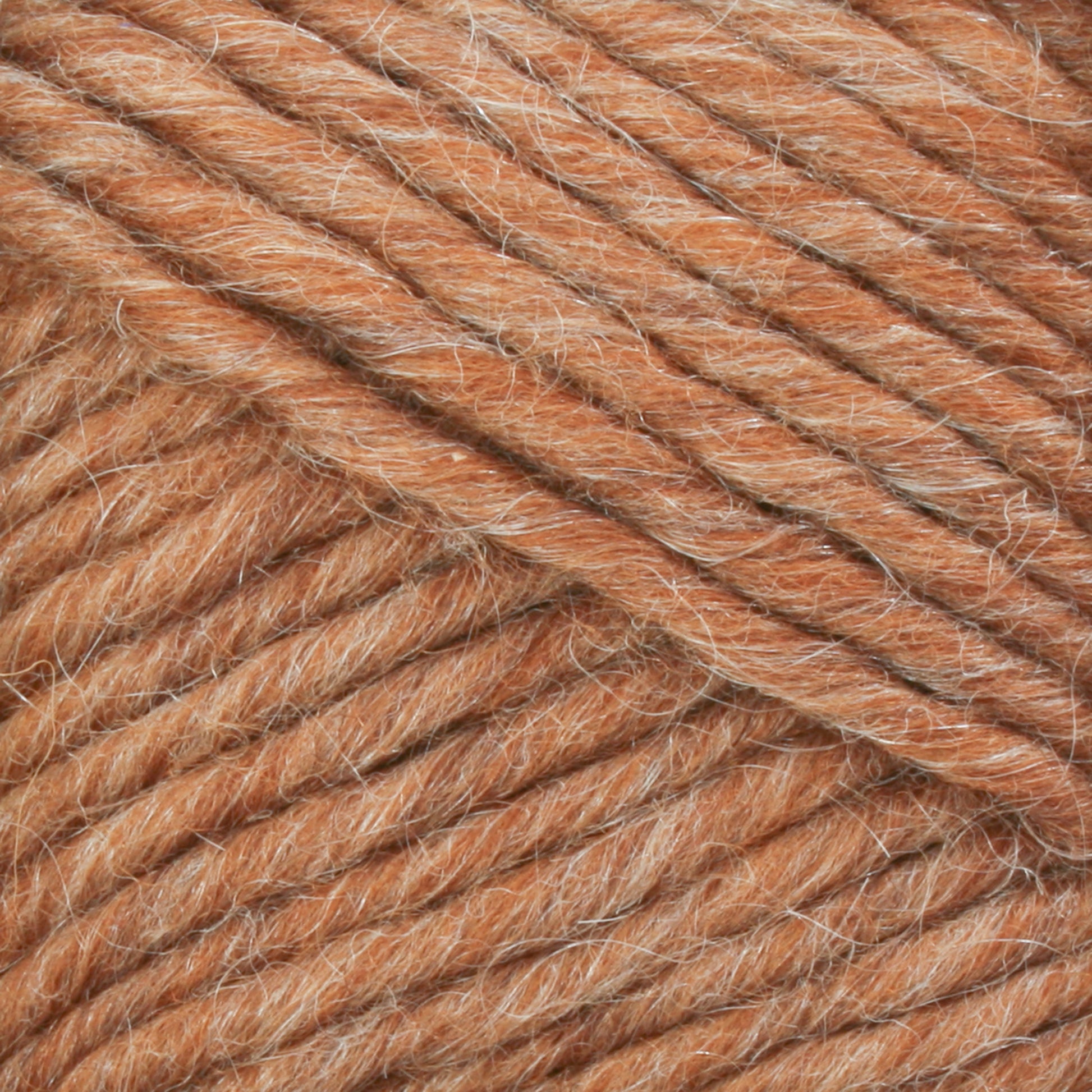 Close-up image of Brown Sheep's Lamb's Pride Bulky Yarn, featuring a thick, textured, and twisted strand in a light brown or tan color. The fibers appear soft and slightly fuzzy, creating a cozy and warm appearance reminiscent of Icelandic sweaters—perfect for knitters and crocheters.