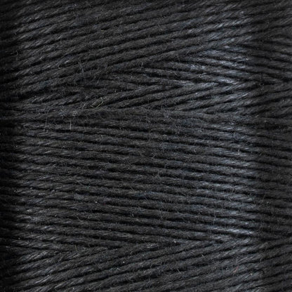 Close-up image of the 16/5 Linen Rug Lacing (Black) by Stuart C. Hurlbert & Co., wound tightly on a spool, showcasing the texture and strands of the fibers. The surface appears slightly shiny with fine, uniform lines of thread, reflecting its strength and smoothness.