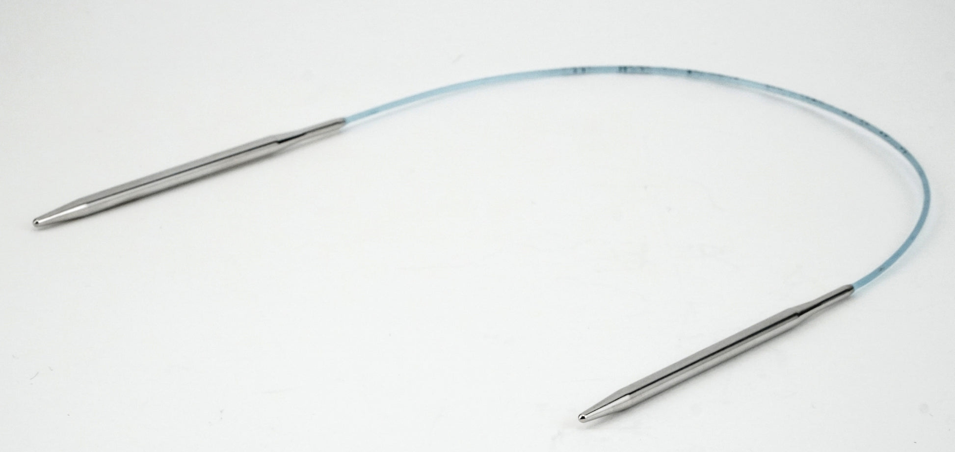 The Addi Turbo Circular Knitting Needles by Skacel feature two metal tips connected by a flexible plastic cable, making them perfect for knitting delicate projects such as cuffs, collars, and doll clothes. Photographed against a plain white background.