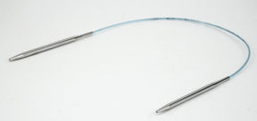 The Addi Turbo Circular Knitting Needles by Skacel feature two metal tips connected by a flexible plastic cable, making them perfect for knitting delicate projects such as cuffs, collars, and doll clothes. Photographed against a plain white background.