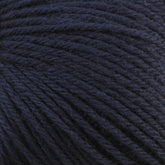 Close-up of a dark blue ball of Baby Blatt by Anny Blatt, showcasing the detailed texture of the tightly wound fibers. The yarn appears soft and slightly fuzzy with a rich, deep hue. This fingering weight yarn from Essentially Felt Studio & Fine Yarn is machine washable, making it perfect for delicate projects.