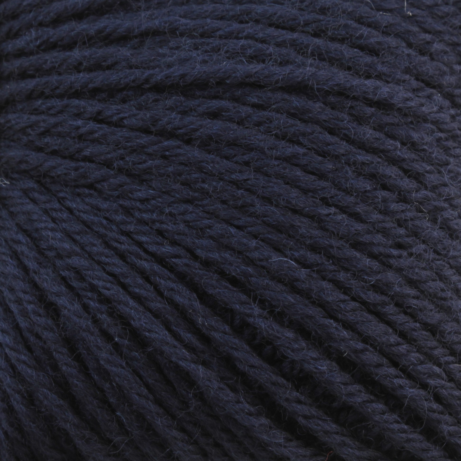 Close-up of a dark blue ball of Baby Blatt by Anny Blatt, showcasing the detailed texture of the tightly wound fibers. The yarn appears soft and slightly fuzzy with a rich, deep hue. This fingering weight yarn from Essentially Felt Studio & Fine Yarn is machine washable, making it perfect for delicate projects.