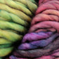 Close-up image of two thick, colorful yarn skeins. The left skein features shades of green and yellow, while the right skein showcases a gradient of pink, purple, and blue hues. Perfect for quick-to-knit projects, Malabrigo Rasta by Malabrigo Yarn is soft and fluffy—ideal for enthusiasts of this super bulky yarn.