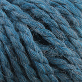 Close-up image of thick, twisted strands of Baby Alpaca Grande by Plymouth Yarn Co. in a blue color with some grey fibers interwoven. The texture appears ultra-soft and slightly fuzzy, suggesting a luxurious wool or wool-blend material. This bulky weight yarn is coiled and tightly packed together.