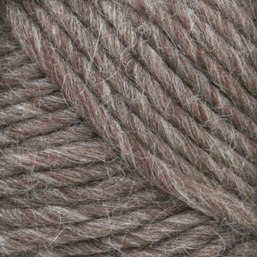 A close-up image of Lamb's Pride Bulky Yarn by Brown Sheep reveals thick, brown threads with visible fibers interwoven in a tight, textured pattern. Reminiscent of the quality seen in Icelandic sweaters, this yarn boasts a consistent hue with some variations and a slightly fuzzy appearance. Perfect for knitters and crocheters seeking premium material.