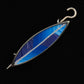 The Songbird Shawl Pin by Bonnie Bishoff Designs is a marquise-shaped accessory with a metallic frame, featuring a blue and white feather-like pattern on the inside. This handmade piece from Bonnie Bishoff has a hooked end and a pointed end, set against a black background.