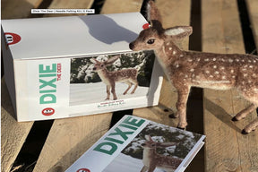 Packaging of "Animal Sculpture Felting Kits" by Europa Wools Ltd, featuring "Dixie the Deer." The box displays an image of a felted, realistic animal and includes wool fibers, materials, and instructions for crafting. A completed felted deer model stands next to the box on a wooden surface. A booklet next to the box reads "DIXIE.