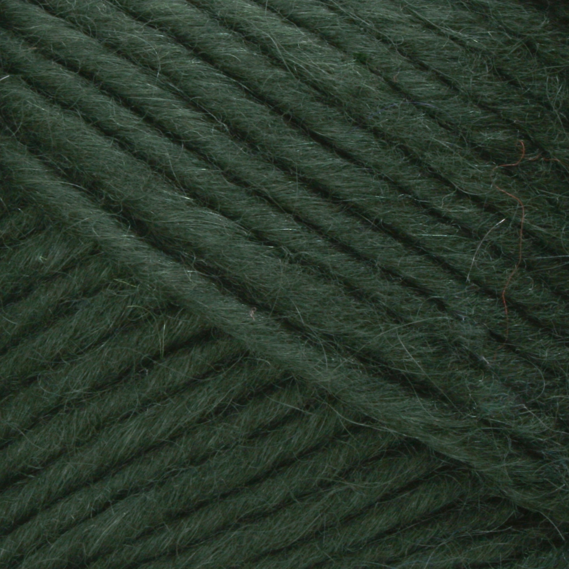 Close-up of Brown Sheep's Lamb's Pride Bulky Yarn in green, featuring a slightly fuzzy texture wound tightly in parallel strands. The fibers appear soft and thick, making it ideal for knitters and crocheters crafting warm garments such as Icelandic sweaters. The image highlights the yarn's even and consistent texture.