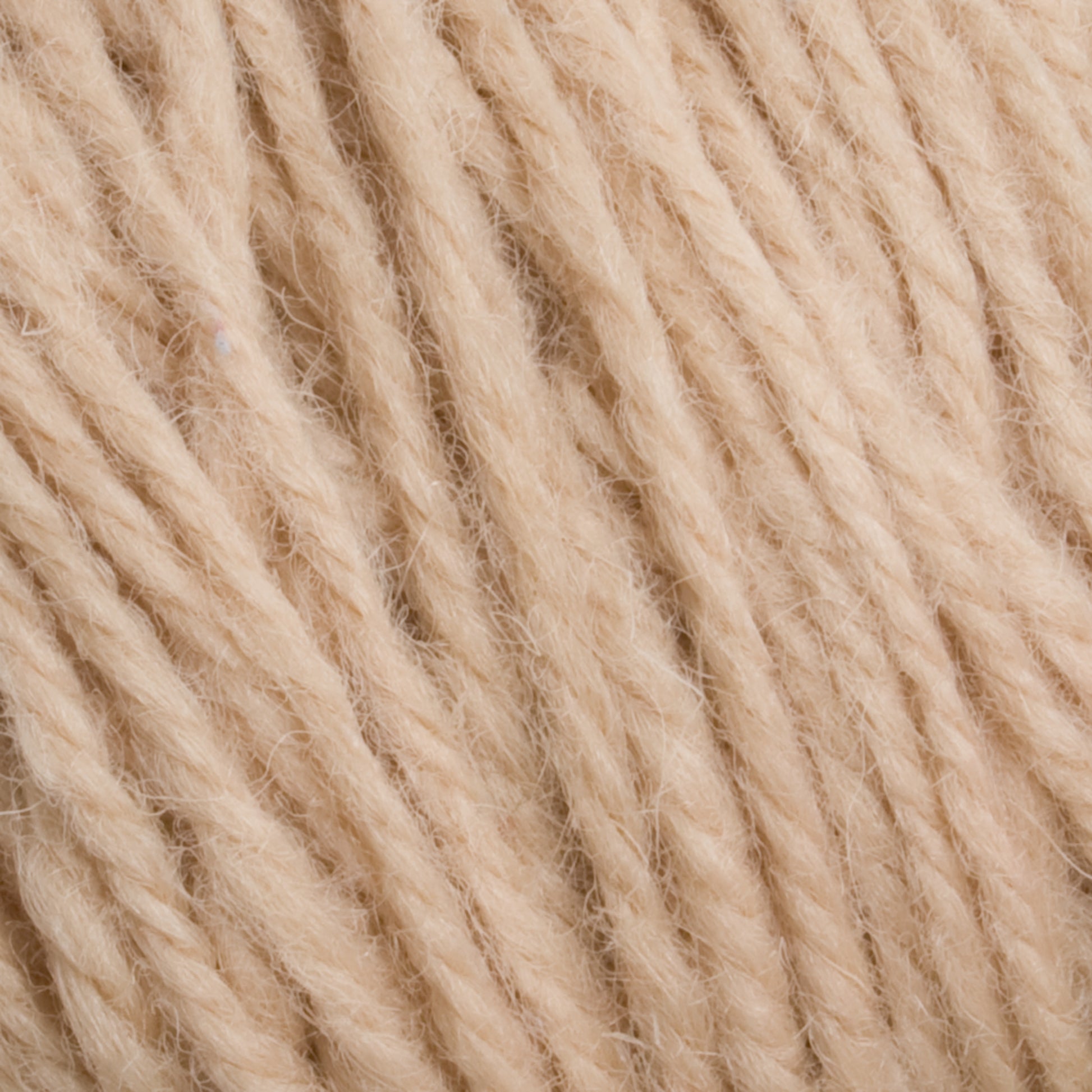 Close-up image of Halcyon Deco Rug Wool by Caledonian Dye Works in a beige hue. The soft, twisted fibers are tightly packed, showcasing the texture and detail of the material. The strands appear thick and slightly fuzzy, indicating a potential use for knitting or crocheting versatile yarn projects.