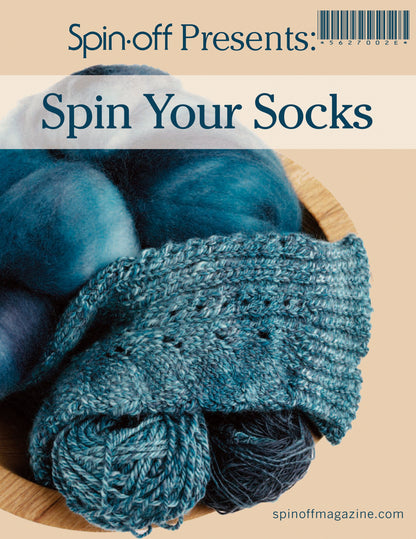 Cover of "Spin-Off Presents: Spin Your Socks: eBook Printed Copy" by Long Thread Media. It features blue and white yarn in a bowl, with a pair of partially knitted blue socks resting on top. At the bottom, the magazine's website, spinoffmagazine.com, is listed.