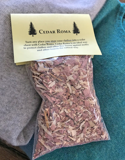 A package of Cedar Roma Shavings rests on a fabric surface. The label highlights Cedar Roma's effectiveness in safeguarding clothes and linens from moths and insects.