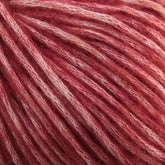 A close-up of soft, textured luxury yarn in shades of pink and white. The aran weight Katia Cotton-Merino yarn strands from Knitting Fever / Euro Yarns are densely packed and display varying hues from deep pink to lighter, almost white tones, creating a beautiful variegated pattern. The Merino wool fibers appear fluffy and plush.