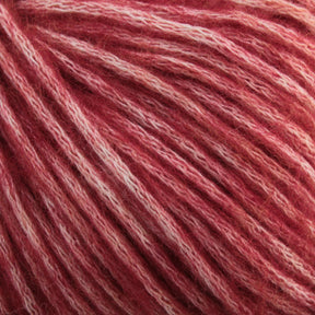 A close-up of soft, textured luxury yarn in shades of pink and white. The aran weight Katia Cotton-Merino yarn strands from Knitting Fever / Euro Yarns are densely packed and display varying hues from deep pink to lighter, almost white tones, creating a beautiful variegated pattern. The Merino wool fibers appear fluffy and plush.