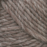 Close-up image of Lamb's Pride Bulky Yarn from Brown Sheep, showcasing its thick, twisted brown fibers. This yarn, ideal for knitters and crocheters, has a slightly fuzzy texture with tightly wound strands.