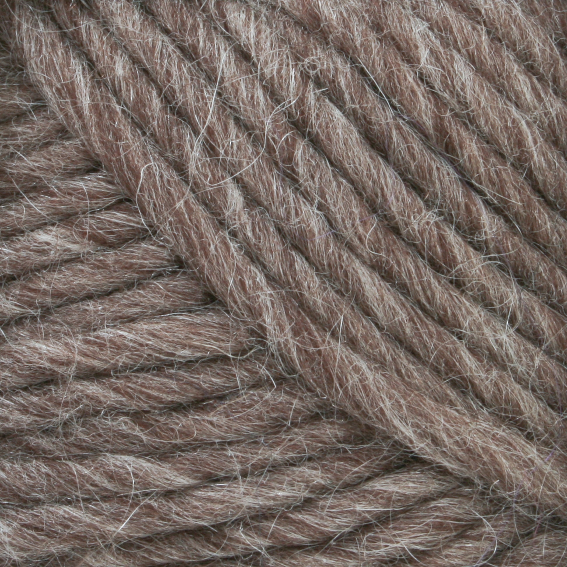 Close-up image of Lamb's Pride Bulky Yarn from Brown Sheep, showcasing its thick, twisted brown fibers. This yarn, ideal for knitters and crocheters, has a slightly fuzzy texture with tightly wound strands.