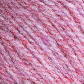 Close-up of pink and purple textured yarn, tightly wound into a ball. The yarn has a soft, fluffy appearance, with individual fibers visible, showcasing a heathered blend of colors. This worsted weight yarn exemplifies the quality of Bartlettyarns' Bartlettyarns Maine Wool Yarn.