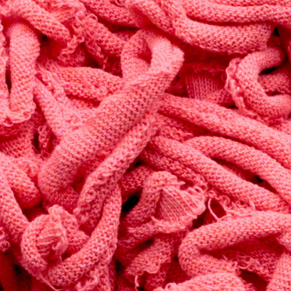 A close-up image of tangled, knitted fabric in various shades of pink from the Harrisville Potholder Loops - Traditional Size Mini Pack by Friendly Loom. The detailed texture showcases cotton loops and knots, giving the fabric a soft and fibrous appearance, which creates a visually intricate and complex pattern.